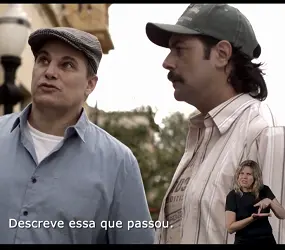 Frame do filme “Teu mundo não cabe nos meus olhos”, com os atores Edson Celulari e Leonardo Machado. Eles aparecem do peito para cima. Estão conversando em uma rua -  ao fundo, percebe-se um poste de luz, a parede de uma casa, a copa de uma árvore. Celulari usa uma boina. Está de camisa cinza com o primeiro botão aberto, deixando ver a camiseta branca por baixo.  Leonardo usa um boné preto. Está de camiseta bege por baixo de uma camisa da mesma cor, com os botões abertos.